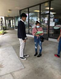 Canvasser speaking with a voter outside a storefront